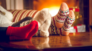 Feet with festive socks on up on a table in front of a fireplace